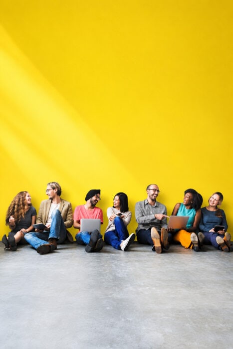 Diverse Teamwork Against A Yellow Wall